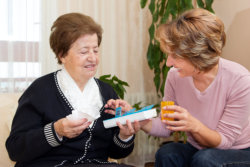 caregiver give a medicine to an old woman